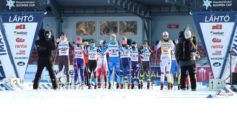 SM-hiihdot 2022, lähtö hiihtäjät rivissä lähtöpaikalla. Kaksi kameramiestä kuvaa hiihtäjiä.