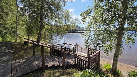 Close-up of a wooden brown terrace and stairs on the shore of a blue lake